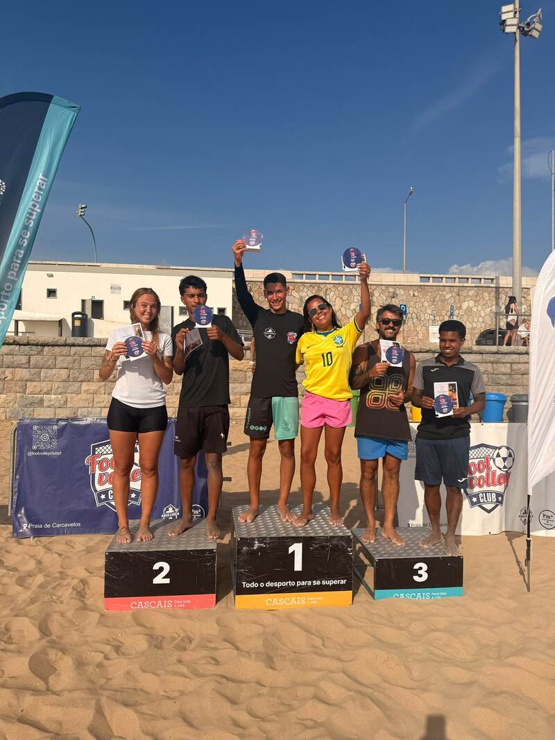Podium with six winners holding trophies on Carcavelos beach