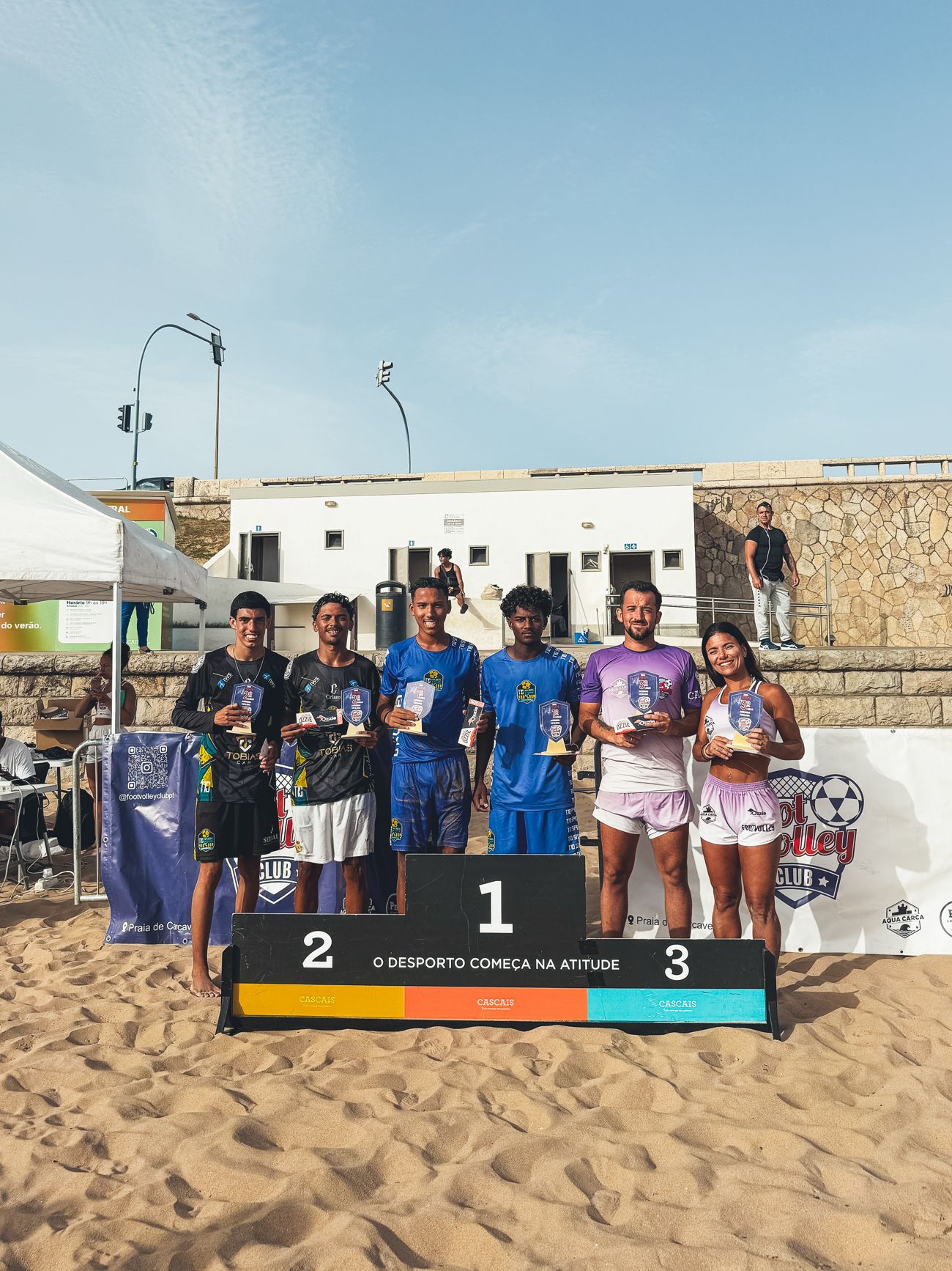 Podium with six winners holding trophies at a Footvolley Club tournament